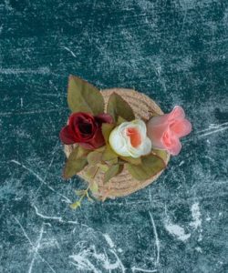 artificial-colorful-roses-clay-vase-trivet-blue-background_114579-82772